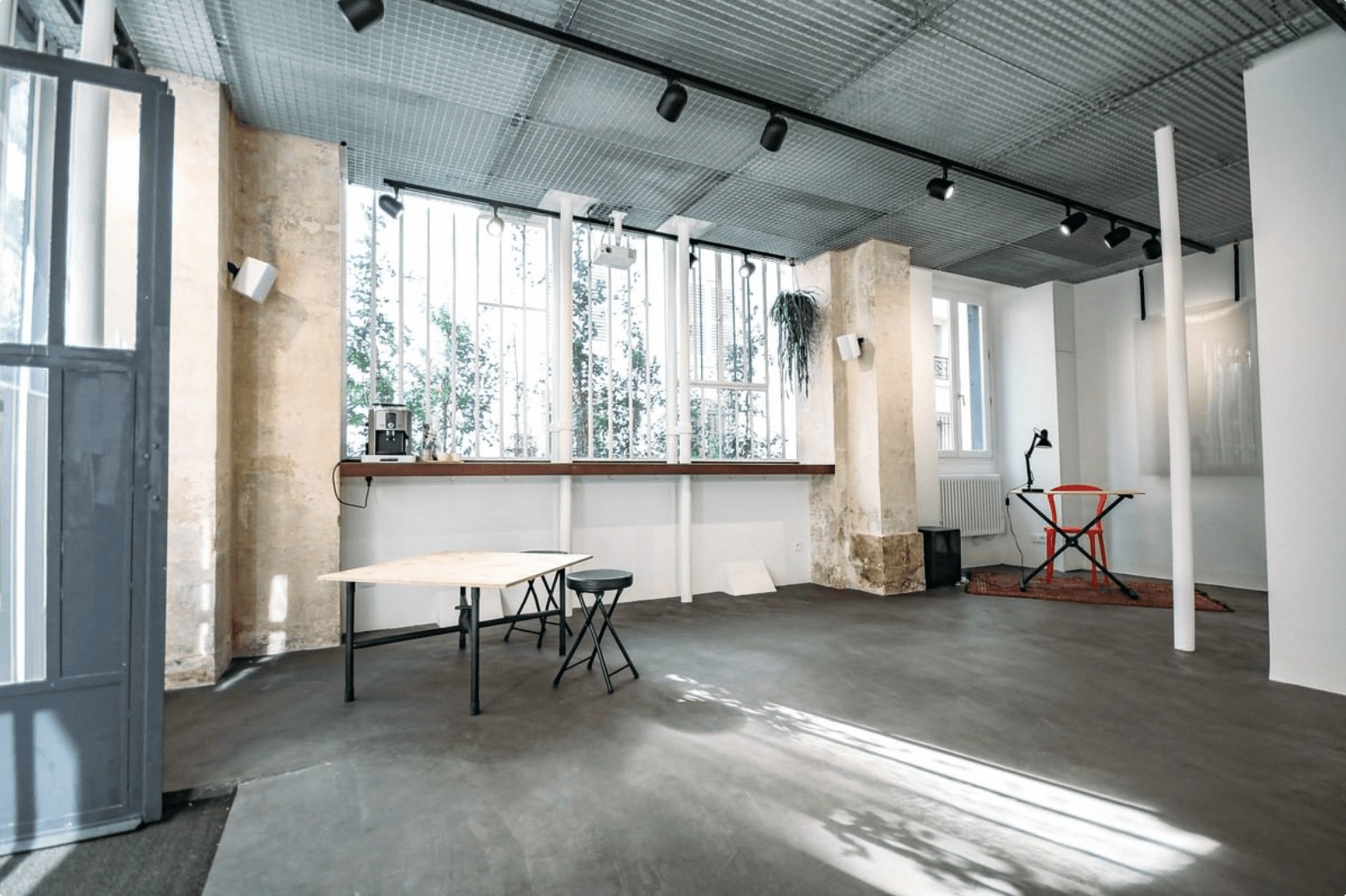 Galerie intimiste et lumineuse avec du béton ciré au sol et de la taule au plafond pour organiser un événement atypique