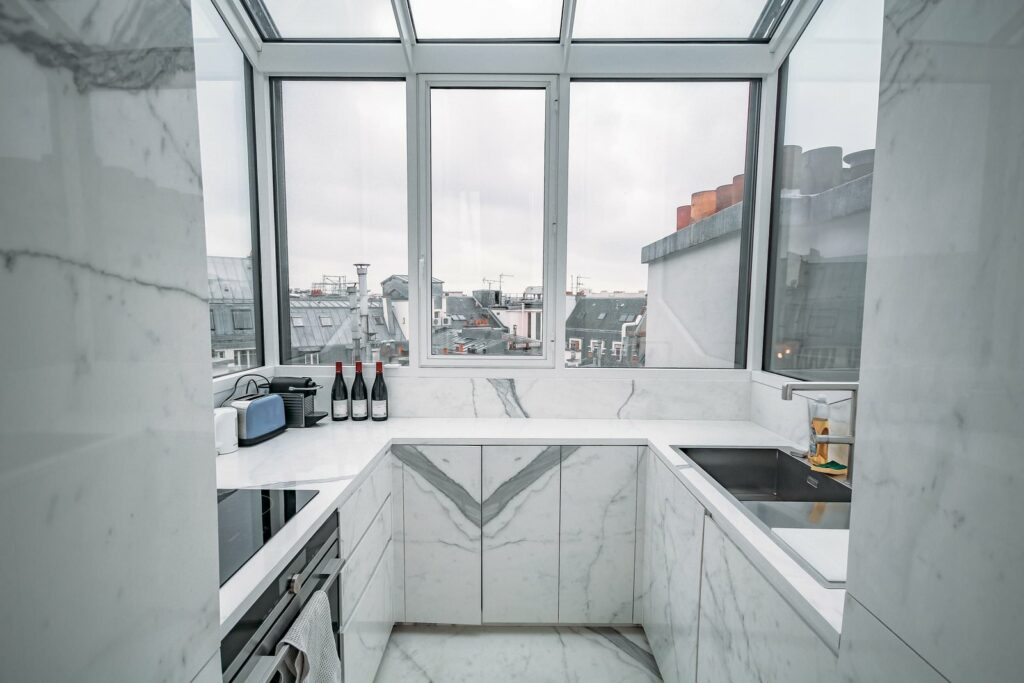 Une cuisine faite de marbre blanc, face à une sublime vue sur les toits de Paris. Cette cuisine est même  trop bien pour un magazine.